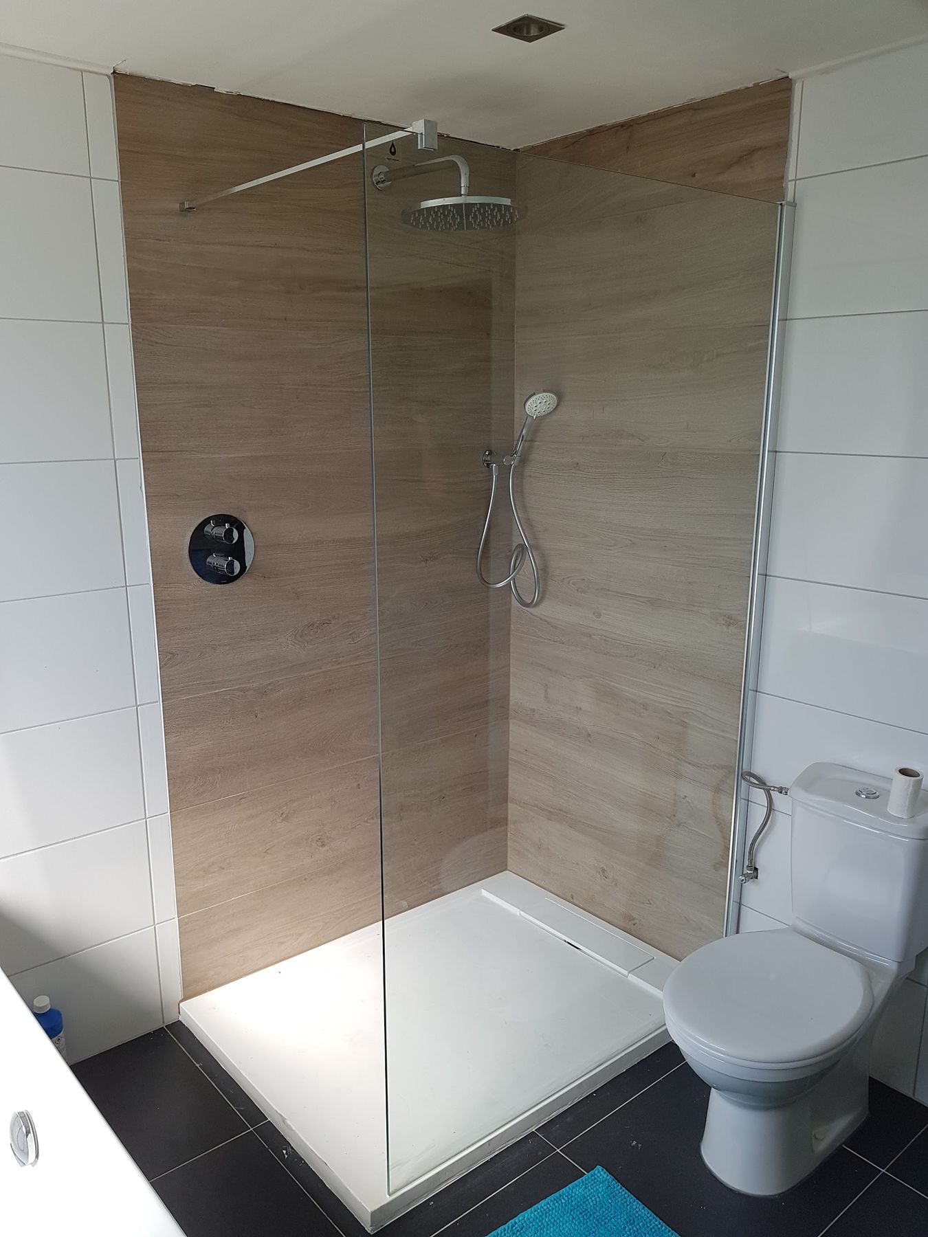 Inloopdouche met houtlook wandtegels, glazen wand, regendouche en donkere vloertegels