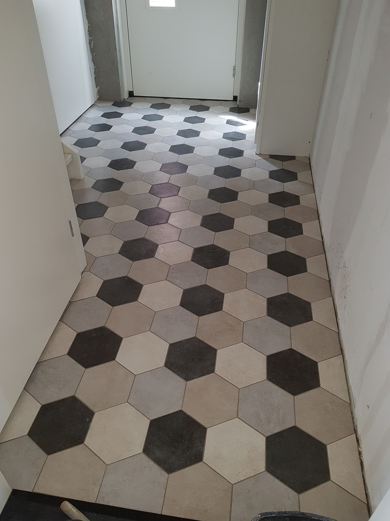 Halvloer van zwarte, grijze en witte hexagontegels